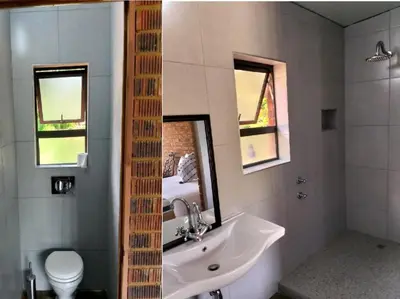 a bathroom with a sink and a toilet and a mirror at Kataluma in Pretoria