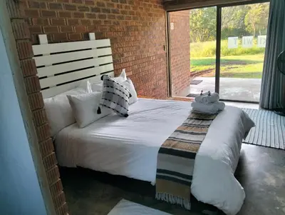 a bedroom with a white bed with a brick wall at Kataluma in Pretoria