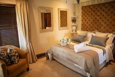 a bedroom with a large bed and a chair at White River Country Estate - Self Catering - AMH Home in White River
