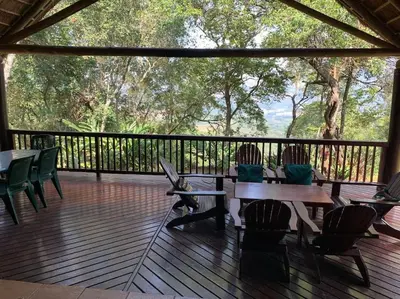 a wooden deck with tables and chairs on it at Schoemanskloof, Mpumalanga - Clancy Forest Lodge in Rietvlei