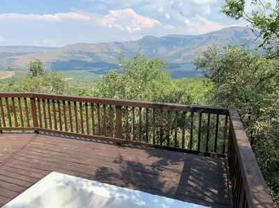 a wooden balcony with a view of the mountains at Schoemanskloof, Mpumalanga - Clancy Forest Lodge in Rietvlei