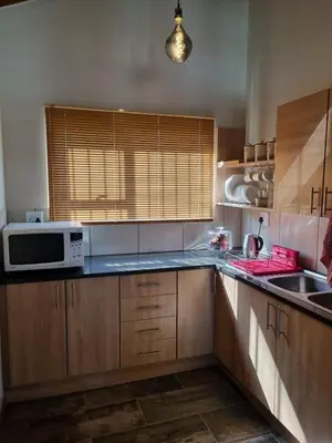a kitchen with wooden cabinets and a microwave oven at Stay@Walter in Pretoria