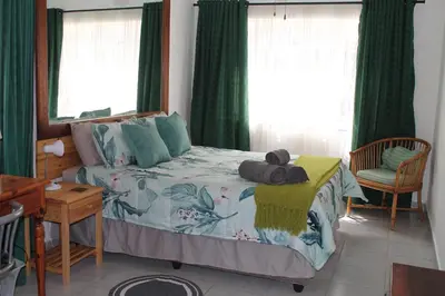 a bedroom with a bed with green curtains at Bush Lilly Cottage in Hazyview