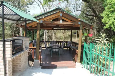 a wooden pergola with a table and chairs on a deck at Bush Lilly Cottage in Hazyview