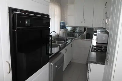a kitchen with a sink and a black refrigerator at Bush Lilly Cottage in Hazyview