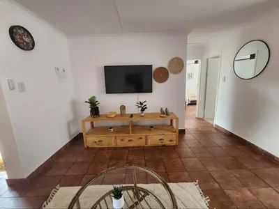 a living room with a television on a white wall at The Grace in Pretoria