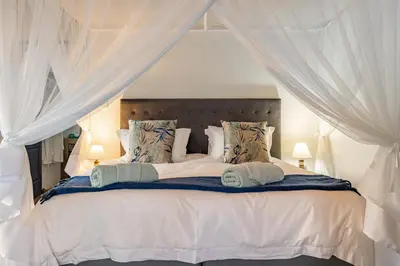 a bedroom with a large white bed with curtains at Blue Goose Bush Retreat in Marloth Park
