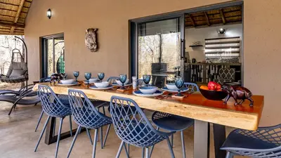 a dining room with a large wooden table and chairs at Blue Goose Bush Retreat in Marloth Park