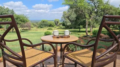a table and chairs on a patio with a view of a field at Itaga Luxury Private Game Lodge in Bela-Bela