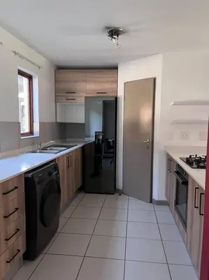 a kitchen with a washer and a sink and a dishwasher at Iyana Place in Midrand