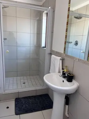 a white bathroom with a sink and a shower at Iyana Place in Midrand