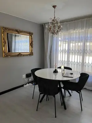 a dining room with a table and chairs and a mirror at Iyana Place in Midrand