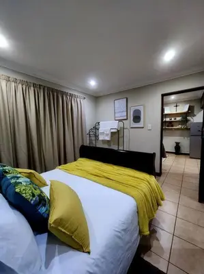 a bedroom with two beds and a yellow blanket at Lily Rest Garden Cottage in Pretoria