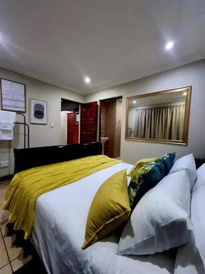 a bedroom with a large bed with yellow sheets and pillows at Lily Rest Garden Cottage in Pretoria