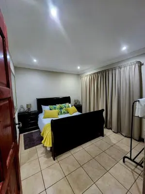 a bedroom with a bed with yellow pillows at Lily Rest Garden Cottage in Pretoria