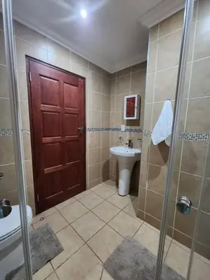 a bathroom with a shower and a toilet and a sink at Lily Rest Garden Cottage in Pretoria