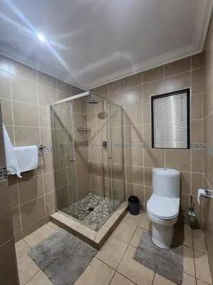 a bathroom with a shower and a toilet at Lily Rest Garden Cottage in Pretoria