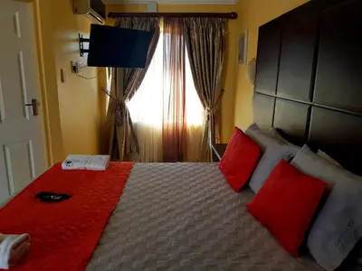 a bedroom with a bed with red pillows and a window at Muofhe Graceland Lodge in Thohoyandou