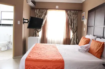 a bedroom with a bed with a television and a window at Muofhe Graceland Lodge in Thohoyandou