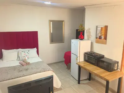 a small bedroom with a bed and a refrigerator at Karee Gardens B&B in Springs