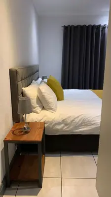 a bed with yellow pillows and a table in a room at CALDESMO Private Apartment in Pretoria