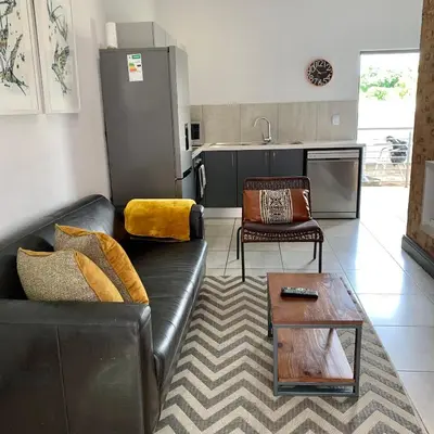 a living room with a leather couch and a table at CALDESMO Private Apartment in Pretoria