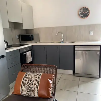 a kitchen with a sink and a chair with a pillow at CALDESMO Private Apartment in Pretoria