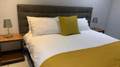 a large bed with white sheets and green pillows at CALDESMO Private Apartment in Pretoria