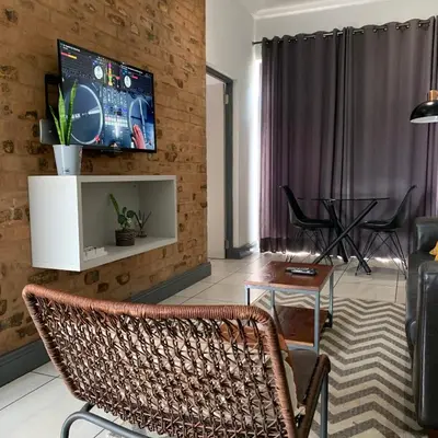 a living room with a tv on a brick wall at CALDESMO Private Apartment in Pretoria