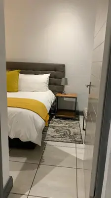 a bedroom with a bed and a side table at CALDESMO Private Apartment in Pretoria