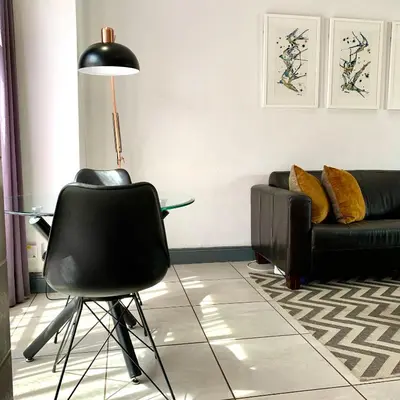a living room with a black chair and a glass table at CALDESMO Private Apartment in Pretoria