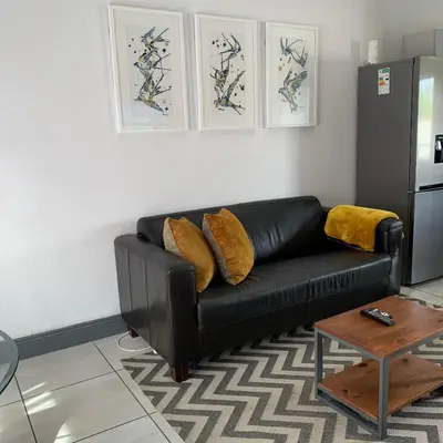 a black leather couch in a living room with a table at CALDESMO Private Apartment in Pretoria