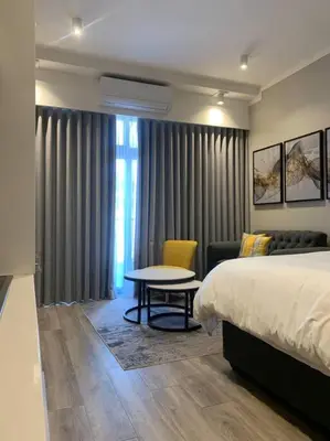 a bedroom with a bed and a table and a couch at Entire Studio Apartment at The Capital Triology in Pretoria