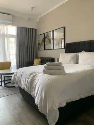 a bedroom with a large bed with white sheets and pillows at Entire Studio Apartment at The Capital Triology in Pretoria