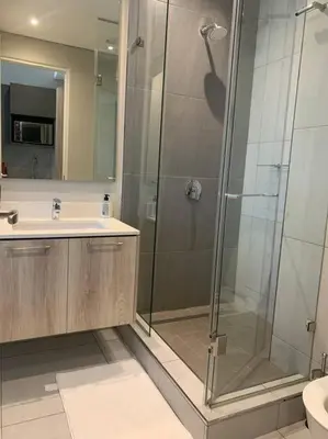 a bathroom with a glass shower and a sink at Entire Studio Apartment at The Capital Triology in Pretoria
