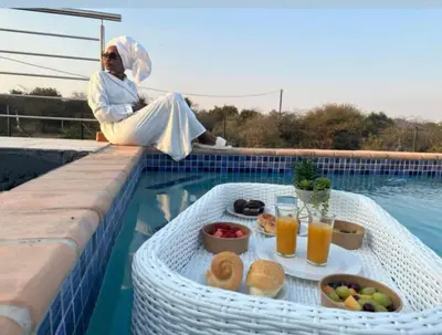 a woman sitting next to a swimming pool with a tray of food at Kings view exclusive villas (KVEV) in Pretoria-Noord