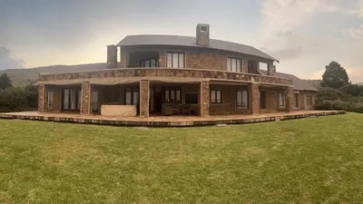 a large house with a roof on a grass field at iDube Lodge Walkersons in Dullstroom