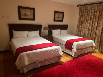 a bedroom with two beds and a red rug at iDube Lodge Walkersons in Dullstroom