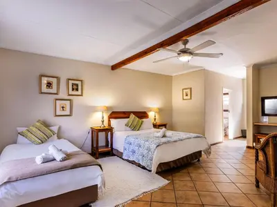 a bedroom with two beds and a ceiling fan at Schoongezich Guesthouse in Pretoria
