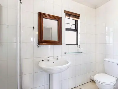 a bathroom with a sink and a toilet and a mirror at Schoongezich Guesthouse in Pretoria