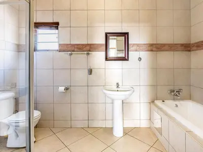 a bathroom with a sink and a toilet and a tub at Schoongezich Guesthouse in Pretoria