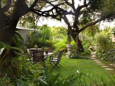 a garden with a table and chairs under a tree at Schoongezich Guesthouse in Pretoria