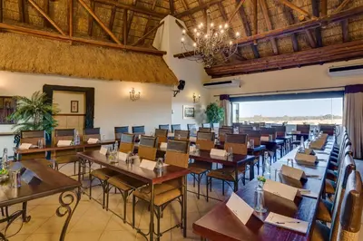 a dining room with tables and chairs and a chandelier at Zebula Golf Estate and Spa - Zebula Golfers Lodge in Mabula