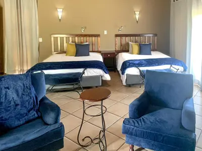 a hotel room with two beds and a couch and chairs at Zebula Golf Estate and Spa - Zebula Golfers Lodge in Mabula