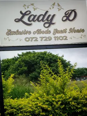 a sign for a store with trees in the background at Lady D Exclusive Abode in Polokwane