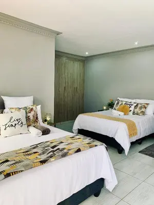 a bedroom with two beds with white sheets at Lady D Exclusive Abode in Polokwane