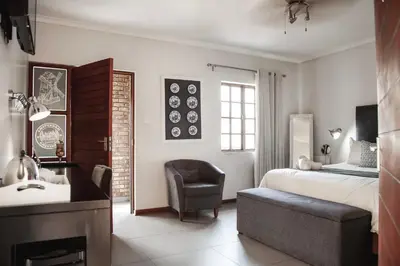 a bedroom with a bed and a chair and a sink at Yalla Yalla Boutique Hotel in Witbank