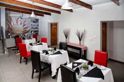 a restaurant with white tables and red chairs at Yalla Yalla Boutique Hotel in Witbank