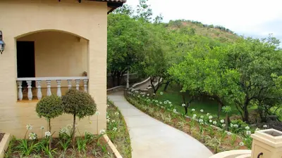 a walkway next to a building with trees and a hill at La Villa Vita in Nelspruit