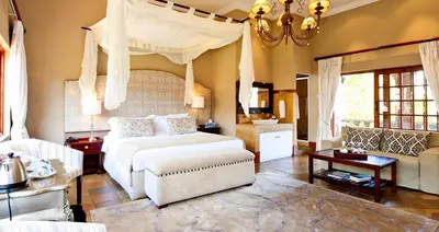 a bedroom with a bed and a living room at La Villa Vita in Nelspruit